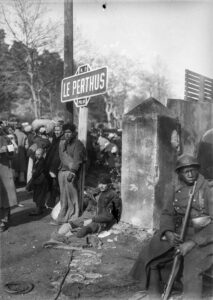 Homme appuyé sur le panneau du Perthus